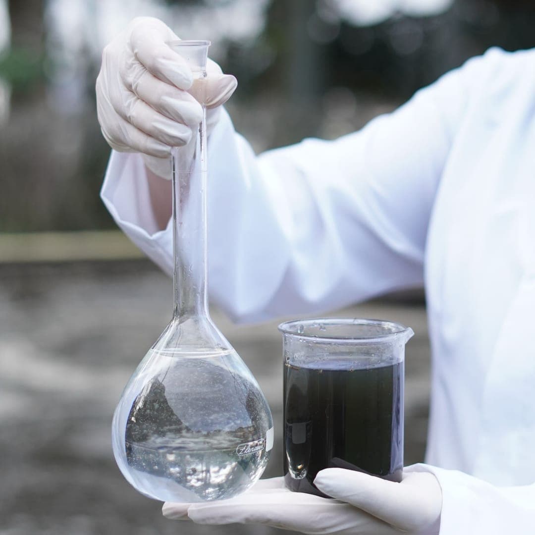 Análise de água e efluentes em laboratório, com amostras em vidraria.